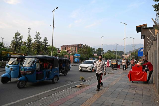 This photograph taken on July 6, 2026 shows a pedestrian walking on a footpath along a road in Srinagar. In India, a pavement can be many things -- hawking site, parking area, garbage dumping space -- but rarely what it is meant to be: a safe unobstructed path to walk on. (Photo by TAUSEEF MUSTAFA / AFP)