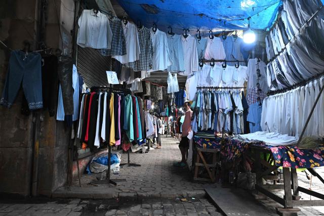This photograph taken on July 6, 2026 shows garment vendors selling clothes on a footpath along a road in Kolkata. In India, a pavement can be many things -- hawking site, parking area, garbage dumping space -- but rarely what it is meant to be: a safe unobstructed path to walk on. (Photo by Dibyangshu SARKAR / AFP)
