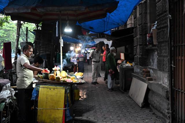 This photograph taken on July 6, 2026 shows a fruit vendor selling papayas on a footpath along a road in Kolkata. In India, a pavement can be many things -- hawking site, parking area, garbage dumping space -- but rarely what it is meant to be: a safe unobstructed path to walk on. (Photo by Dibyangshu SARKAR / AFP)