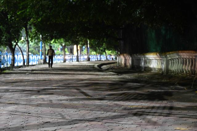 This photograph taken on July 6, 2026 shows a pedestrian walking on a footpath along a road in Kolkata. In India, a pavement can be many things -- hawking site, parking area, garbage dumping space -- but rarely what it is meant to be: a safe unobstructed path to walk on. (Photo by Dibyangshu SARKAR / AFP)