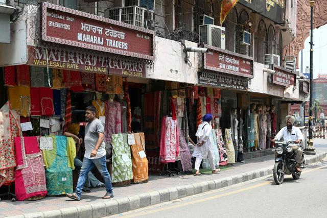 This photograph taken on July 7, 2026 shows pedestrians walking on a footpath along a street in Amritsar. In India, a pavement can be many things -- hawking site, parking area, garbage dumping space -- but rarely what it is meant to be: a safe unobstructed path to walk on. (Photo by Narinder NANU / AFP)