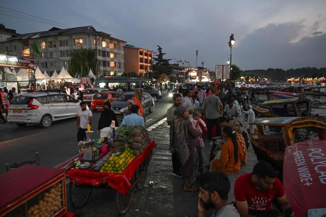 This photograph taken on July 7, 2026 shows pedestrians walking along a footpath at the Dal Lake in Srinagar. In India, a pavement can be many things -- hawking site, parking area, garbage dumping space -- but rarely what it is meant to be: a safe unobstructed path to walk on. (Photo by TAUSEEF MUSTAFA / AFP)