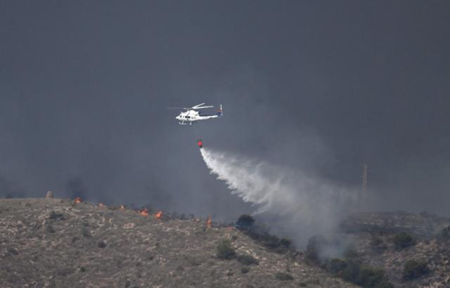 A picture taken on July 10, 2026 shows a water bombing helicopter on the site of a wildfire that killed 11 near Los Gallardos, in Almeria Province. Eleven people were killed and 19 are missing after a wildfire in Bedar, in Los Gallardos district, with four victims who may have been British who were burned in their car, authorities said. (Photo by JOSE JORDAN / AFP)