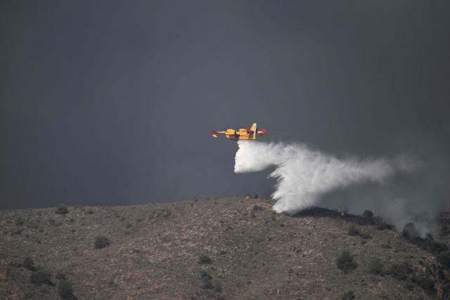 A picture taken on July 10, 2026 shows a Canadair CL-415 water bombing aircraft on the site on a wildfire that killed 11 near Los Gallardos, in Almeria Province. Eleven people were killed and 19 are missing after a wildfire in Bedar, in Los Gallardos district, with four victims who may have been British who were burned in their car, authorities said. (Photo by JOSE JORDAN / AFP)