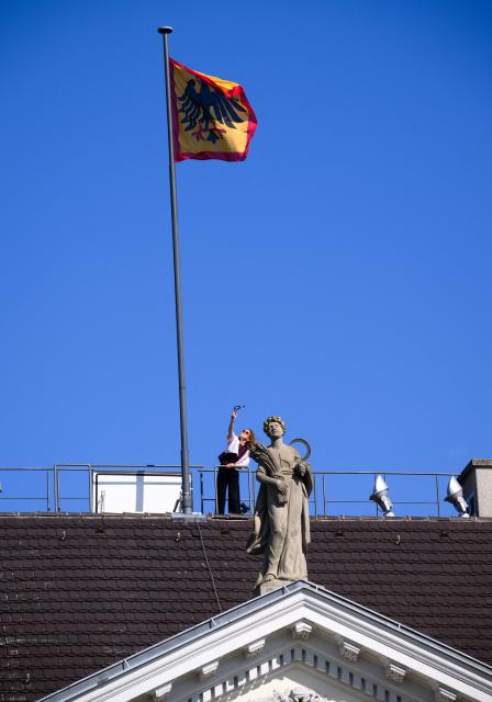 A member of the social media team of the Federal German President's Office films the Federal President's flag still fluttering on the roof of the presidential Bellevue Palace before the standard is taken down to be raised again at the President's temporary residence, on July 10, 2026 in Berlin. The Bellevue Palace will undergo extensive renovation. For up to eight years, the Federal President’s Office will move to an interim residence, the "Amtssitz am Spreebogen". (Photo by Bernd von Jutrczenka / POOL / AFP)