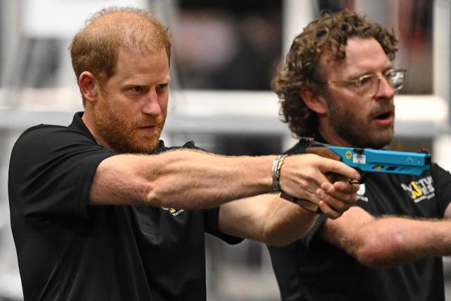 Britain's Prince Harry, Duke of Sussex, stands alongside Games medallist John-James (JJ) Chalmers (R) as he holds a Laser Pistol during the shooting aspect of Laser Run, at an event to mark the 'Invictus Games Birmingham 2027: One Year To Go', at the NEC in Birmingham, central England on July 10, 2026. (Photo by Oli SCARFF / AFP)