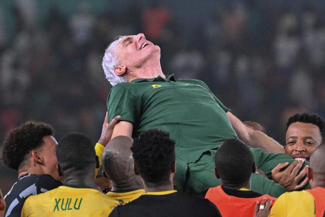 (FILES) South Africa's head coach Hugo Broos is lifted in the air by South African players after they won the Africa Cup of Nations (CAN) 2024 third place play-off football match between South Africa and Democratic Republic of Congo at Felix Houphouet-Boigny Stadium in Abidjan on February 10, 2024. Candidates, including Pitso Mosimane, have applied to succeed Hugo Broos as coach of South Africa after the exit of the Belgian was confirmed, a national football association official told AFP on July 10. "Hugo may continue to work with the national team, but in a different capacity," said the insider, who requested anonymity as he is not an official spokesperson. (Photo by Sia KAMBOU / AFP)
