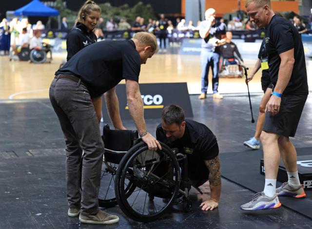 Britain's Prince Harry, Duke of Sussex, helps a competitor who fell back in to their wheelchair during a display of Hybrid Athletics, at an event to mark the 'Invictus Games Birmingham 2027: One Year To Go', at the NEC in Birmingham, central England on July 10, 2026. (Photo by Darren Staples / AFP)