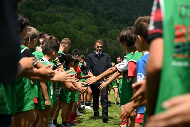 France's President Emmanuel Macron (C) checks hands with children as he visits sports facilities in Loudenvielle, south-western France, on July 10, 2026 (Photo by Lionel BONAVENTURE / POOL / AFP)