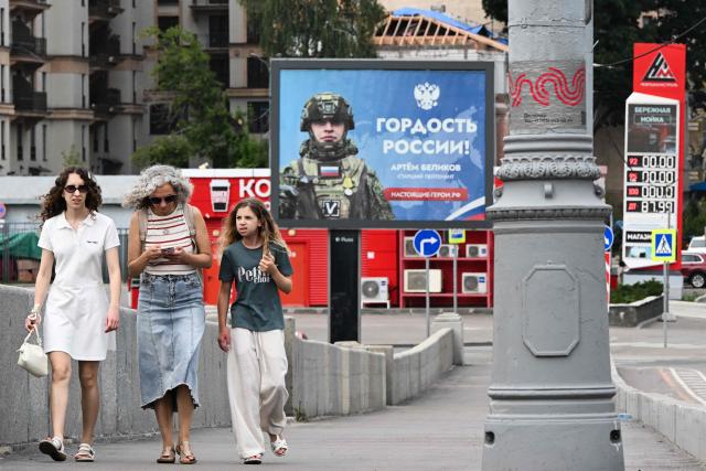 People walk in front of a billboard honouring a participant in Russia's military action in Ukraine and reading "Pride of Russia!" and a Neftmagistral gas station pylon which shows that there is no gasoline at the station in Moscow on July 10, 2026. Russia -- one of the world's largest oil producers -- has introduced a swath of restrictions on petrol sales across the country, as Ukrainian strikes on its refineries, depots and logistics crimp domestic supply. Several regions have introduced rationing, while some gas stations and chains have sold out or closed due to a lack of supplies. (Photo by Igor IVANKO / AFP)