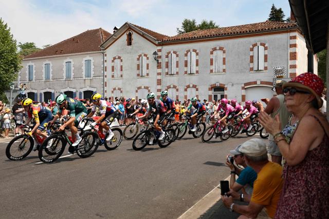 The pack of riders (peloton) cycles through the town of Luxey during the 7th stage of the 113th edition of the Tour de France cycling race, 175,1 km between Hagetmau and Bordeaux in southwestern France, on July 10, 2026. (Photo by Anne-Christine POUJOULAT / AFP)