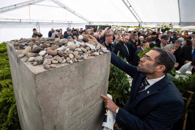 A participant pays tribute by placing a stone on the memorial to the victims of the Jedwabne massacre during a ceremony honouring the memory of the town's Jewish residents murdered on July 10, 1941 by their Polish neighbours, in Jedwabne, north-eastern Poland, on July 10, 2026. Poland's Jewish community, political leaders and ordinary citizens on July 10 commemorated a massacre of hundreds of Jews killed by their Polish neighbors 85 years ago in the town of Jedwabne in then German-occupied Poland, at a ceremony opposed by far-right demonstrators. (Photo by Wojtek RADWANSKI / AFP)