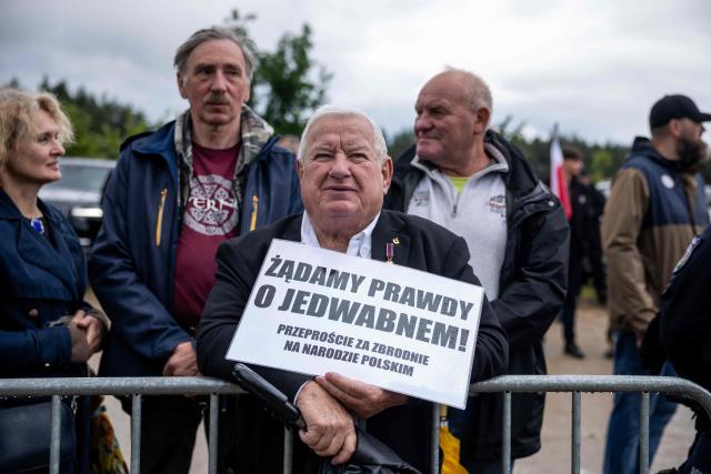 Jerzy Karwowski, who was born in Jedwabne and now lives in the USA, holds a placard reading in Polish 'We demand the truth about Jedwabne  apologise for the crimes against the Polish nation' as he takes part in a gathering of far-right supporters who question the guilt of Polish citizens responsible for the massacre in Jedwabne, placing all the blame on the German pacification unit, in front of the Jedwabne massacre monument during a ceremony honouring the memory of the town's Jewish residents murdered on July 10, 1941 by their Polish neighbours, in Jedwabne, north-eastern Poland, on July 10, 2026. Poland's Jewish community, political leaders and ordinary citizens on July 10 commemorated a massacre of hundreds of Jews killed by their Polish neighbors 85 years ago in the town of Jedwabne in then German-occupied Poland, at a ceremony opposed by far-right demonstrators. (Photo by Wojtek RADWANSKI / AFP)
