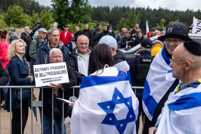 Jerzy Karwowski (2ndL), who was born in Jedwabne and now lives in the USA, holds a placard reading in Polish 'We demand the truth about Jedwabne  apologise for the crimes against the Polish nation' as he takes part in a gathering of far-right supporters who question the guilt of Polish citizens responsible for the massacre in Jedwabne, placing all the blame on the German pacification unit, in front of the Jedwabne massacre monument during a ceremony honouring the memory of the town's Jewish residents murdered on July 10, 1941 by their Polish neighbours, in Jedwabne, north-eastern Poland, on July 10, 2026. Poland's Jewish community, political leaders and ordinary citizens on July 10 commemorated a massacre of hundreds of Jews killed by their Polish neighbors 85 years ago in the town of Jedwabne in then German-occupied Poland, at a ceremony opposed by far-right demonstrators. (Photo by Wojtek RADWANSKI / AFP)