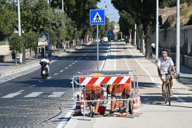 Men work on the special pavement coating to combat the heat compared with classic asphalt near a cycle path at Circo Massimo in Rome on July 10, 2026. (Photo by Alberto PIZZOLI / AFP)