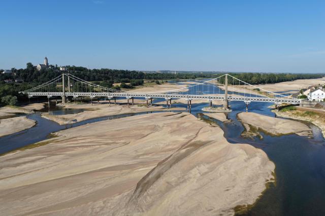 This aerial photograph shows a bridge over the dried out Loire River bed in Loireauxence (Varades), western France, on July 10, 2026. (Photo by Damien MEYER / AFP)