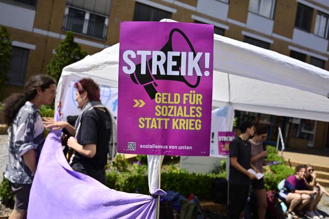 Activists stage a sit-in in front of the German Red Cross (DRK) hospital in Berlin's Wedding district, on July 10, 2026, during a protest against an alleged militarisation of the German healthcare system. The placard reads: "Strike! Money for welfare rathen than war". (Photo by John MACDOUGALL / AFP)