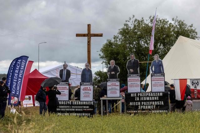 Banners reading 'I do not apologise for Jedwabne – let the perpetrators apologise' and 'Finish the exhumation – put an end to the slanders against Poles – the Jedwabne lie', with cut-out figures depicting Poland's Chief Rabbi Michael Schudrich and former Polish presidents are seen next to a crucifix set up at a gathering of far-right supporters who question the guilt of Polish citizens for the massacre in Jedwabne, on the sidelines of an official ceremony at the Jedwabne massacre monument honouring the memory of the town's Jewish residents murdered on July 10, 1941 by their Polish neighbours, in Jedwabne, north-eastern Poland, on July 10, 2026. Poland's Jewish community, political leaders and ordinary citizens on July 10 commemorated a massacre of hundreds of Jews killed by their Polish neighbors 85 years ago in the town of Jedwabne in then German-occupied Poland, at a ceremony opposed by far-right demonstrators. (Photo by Wojtek RADWANSKI / AFP)