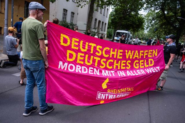 Activists display a banner reading: "German weapons, German cash commit murder around the world" during a protest in Berlin's Wedding district, on July 10, 2026, against the establishment by weapons manufacturer Rheinmetall of a munitions producing unit in the neighbourhood. (Photo by John MACDOUGALL / AFP)