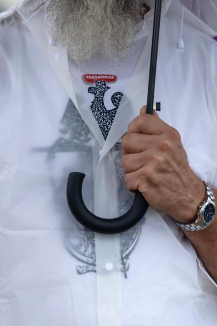 A man holds an umbrella as he wears a t-shirt with the Polish national emblem and lettering reading 'Identity' during a gathering of far-right supporters who question the guilt of the Polish citizens responsible for the massacre in Jedwabne, on the sidelines of an official ceremony at the Jedwabne massacre monument honouring the memory of the town's Jewish residents murdered on July 10, 1941 by their Polish neighbours, in Jedwabne, north-eastern Poland, on July 10, 2026. Poland's Jewish community, political leaders and ordinary citizens on July 10 commemorated a massacre of hundreds of Jews killed by their Polish neighbors 85 years ago in the town of Jedwabne in then German-occupied Poland, at a ceremony opposed by far-right demonstrators. (Photo by Wojtek RADWANSKI / AFP)