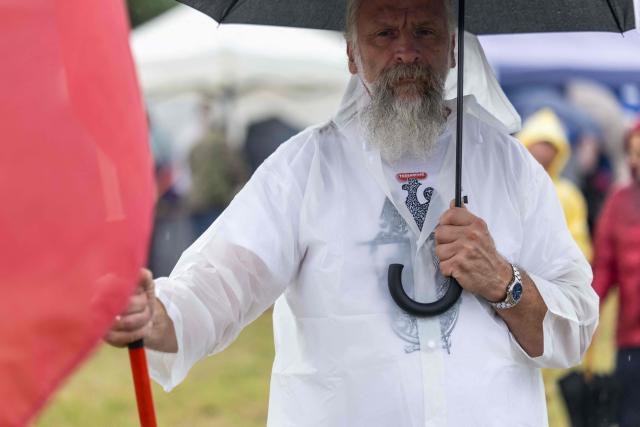 A man holds an umbrella and a Polish national flag at a gathering of far-right supporters who question the guilt of the Polish citizens responsible for the massacre in Jedwabne, on the sidelines of an official ceremony at the Jedwabne massacre monument honouring the memory of the town's Jewish residents murdered on July 10, 1941 by their Polish neighbours, in Jedwabne, north-eastern Poland, on July 10, 2026. Poland's Jewish community, political leaders and ordinary citizens on July 10 commemorated a massacre of hundreds of Jews killed by their Polish neighbors 85 years ago in the town of Jedwabne in then German-occupied Poland, at a ceremony opposed by far-right demonstrators. (Photo by Wojtek RADWANSKI / AFP)