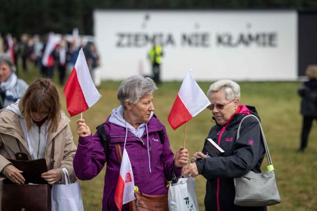 Women hold Polish flags at the gathering of far-right supporters who question the guilt of the Polish citizens responsible for the massacre in Jedwabne and place all the blame on the German pacification unit, on the sidelines of the official ceremonies at the Jedwabne massacre monument honouring the memory of the town's Jewish residents murdered on July 10, 1941 by their Polish neighbours, in Jedwabne, north-eastern Poland, on July 10, 2026. Poland's Jewish community, political leaders and ordinary citizens on July 10 commemorated a massacre of hundreds of Jews killed by their Polish neighbors 85 years ago in the town of Jedwabne in then German-occupied Poland, at a ceremony opposed by far-right demonstrators. (Photo by Wojtek RADWANSKI / AFP)