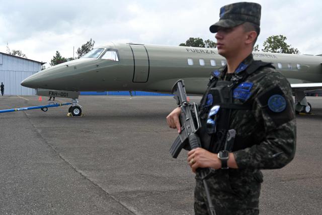 A soldier stands guard by the Honduran presidential airplane, which will be auctioned off as part of austerity measures, as it remains parked at the Hernan Acosta Mejia Air Base in Tegucigalpa on July 10, 2026. The Embraer Legacy 600 jet, which purchase and maintenance have been marred by allegations of corruption, was acquired by Honduran President (2014–2022) Juan Orlando Hernandez. (Photo by Orlando SIERRA / AFP)