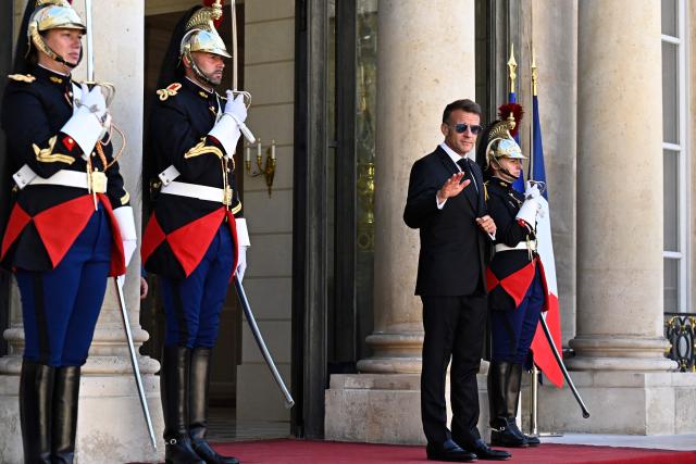 France's President Emmanuel Macron (2ndR) wearing sunglasses reacts as he arrives to greet his South African counterpart at the Elysee Presidential Palace in Paris on July 10, 2026. South African President Cyril Ramaphosa is set to visit the Longueval memorial during the 110th anniversary of the Battle of the Somme in France. (Photo by JULIEN DE ROSA / AFP)