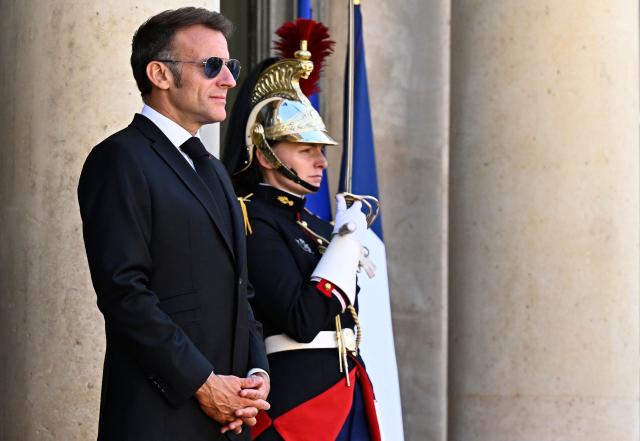 France's President Emmanuel Macron (L) wearing sunglasses reacts as he arrives to greet his South African counterpart at the Elysee Presidential Palace in Paris on July 10, 2026. South African President Cyril Ramaphosa is set to visit the Longueval memorial during the 110th anniversary of the Battle of the Somme in France. (Photo by JULIEN DE ROSA / AFP)