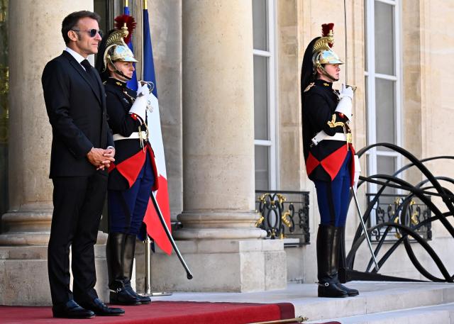 France's President Emmanuel Macron (L) wearing sunglasses reacts as he arrives to greet his South African counterpart at the Elysee Presidential Palace in Paris on July 10, 2026. South African President Cyril Ramaphosa is set to visit the Longueval memorial during the 110th anniversary of the Battle of the Somme in France. (Photo by JULIEN DE ROSA / AFP)
