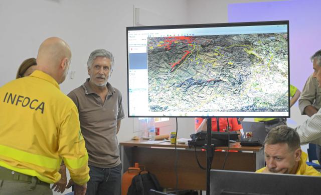 Spain's Interior Minister Fernando Grande-Marlaska listens to a member of the Infoca (Andalusia Wildfire Service) as he visits the advanced command post of the Los Gallardos fire in Turre, in Almeria Province, on July 10, 2026 in the aftermath of a wildfire that killed 12. Twelve people were killed and 23 are missing after a fast-moving wildfire tearing through area in southern Spain, home to many foreign residents. Spain has been sweltering in extreme heat, creating tinderbox conditions favourable for the rapid spread of wildfires. (Photo by Jose JORDAN / AFP)