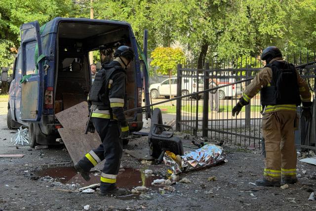 Ukrainian rescuers stand next to the body of a killed person at the site of a Russian airstrike in Zaporizhzhia on July 10, 2026, amid the Russian invasion of Ukraine. (Photo by Darya NAZAROVA / AFP)
