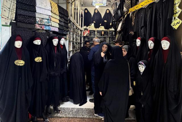 Women shop at a store selling chador gowns at the Grand Reza Bazaar near the shrine of Imam Reza following the funeral of slain Iranian leader Ali Khamenei and his family members in Mashhad on July 10, 2026. Iran on July 10 laid to rest its former supreme leader Ali Khamenei over four months after his killing in an airstrike, as two days of US and Iranian attacks raised fears of a return to all-out war. (Photo by ATTA KENARE / AFP) / 