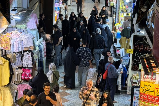 People walk at the Grand Reza Bazaar near the shrine of Imam Reza following the funeral of slain Iranian leader Ali Khamenei and his family members in Mashhad on July 10, 2026. Iran on July 10 laid to rest its former supreme leader Ali Khamenei over four months after his killing in an airstrike, as two days of US and Iranian attacks raised fears of a return to all-out war. (Photo by ATTA KENARE / AFP) / 