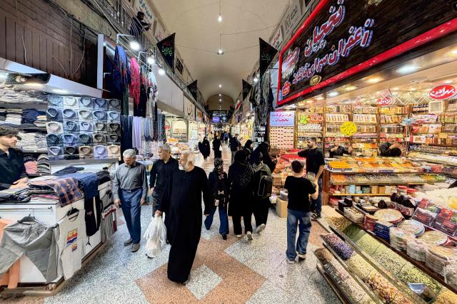 People walk at the Grand Reza Bazaar near the shrine of Imam Reza following the funeral of slain Iranian leader Ali Khamenei and his family members in Mashhad on July 10, 2026. Iran on July 10 laid to rest its former supreme leader Ali Khamenei over four months after his killing in an airstrike, as two days of US and Iranian attacks raised fears of a return to all-out war. (Photo by ATTA KENARE / AFP) / 