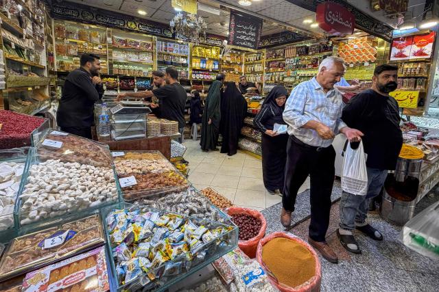 People shop at a store in the Grand Reza Bazaar near the shrine of Imam Reza following the funeral of slain Iranian leader Ali Khamenei and his family members in Mashhad on July 10, 2026. Iran on July 10 laid to rest its former supreme leader Ali Khamenei over four months after his killing in an airstrike, as two days of US and Iranian attacks raised fears of a return to all-out war. (Photo by ATTA KENARE / AFP) / 
