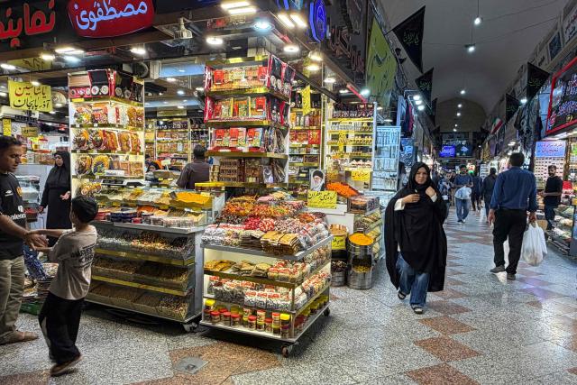 People walk at the Grand Reza Bazaar near the shrine of Imam Reza following the funeral of slain Iranian leader Ali Khamenei and his family members in Mashhad on July 10, 2026. Iran on July 10 laid to rest its former supreme leader Ali Khamenei over four months after his killing in an airstrike, as two days of US and Iranian attacks raised fears of a return to all-out war. (Photo by ATTA KENARE / AFP) / 