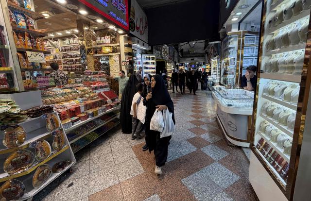 People walk at the Grand Reza Bazaar near the shrine of Imam Reza following the funeral of slain Iranian leader Ali Khamenei and his family members in Mashhad on July 10, 2026. Iran on July 10 laid to rest its former supreme leader Ali Khamenei over four months after his killing in an airstrike, as two days of US and Iranian attacks raised fears of a return to all-out war. (Photo by ATTA KENARE / AFP) / 