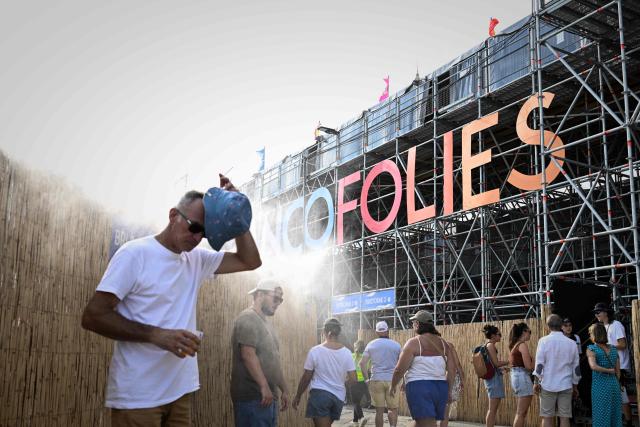 A man cools off under a water mist diffuser as festivalgoers arrive on the opening day of the 42nd Francofolies music festival in La Rochelle, western France, on July 10, 2026, as a heatwave hits France. (Photo by Philippe LOPEZ / AFP)