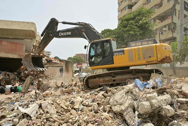 A backhoe removes debris at the site of collapsed buildings in Caraballeda, state of La Guaira, Venezuela, on July 10, 2026, following the June 24 twin earthquakes. The death toll from the powerful double earthquake has risen to at least 3,889, whilst the number of injured remains at almost 17,000, and nearly 18,000 people were left homeless according to the last official reports. (Photo by MARTIN BERNETTI / AFP)