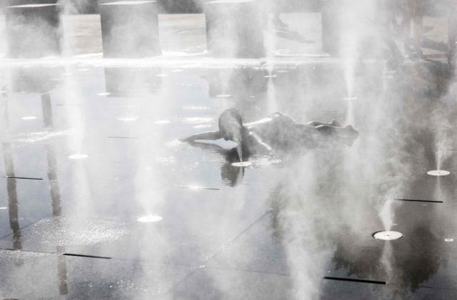 A child plays in a splash pad during a heatwave in Paris on July 10, 2026. (Photo by Behrouz MEHRI / AFP)