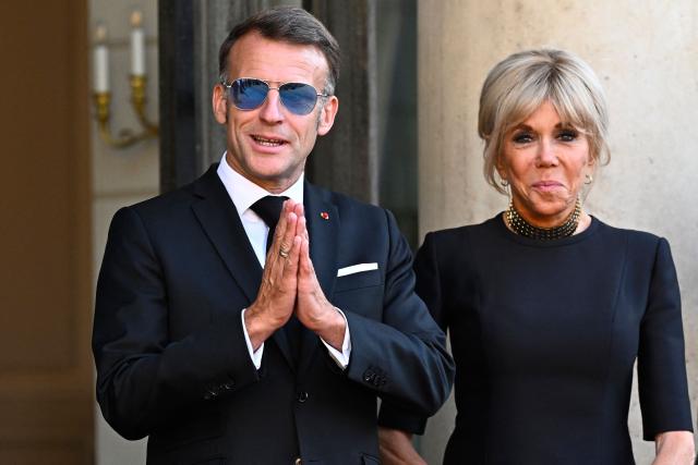 France's President Emmanuel Macron (L) getsures next to his wife Brigitte Macron at The Elysee Presidential Palace ahead of an official state dinner with South Africa's President and representatives in Paris on July 10, 2026. (Photo by JULIEN DE ROSA / AFP)