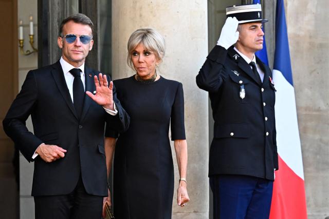 France's President Emmanuel Macron (L) waves next to his wife Brigitte Macron at The Elysee Presidential Palace ahead of an official state dinner with South Africa's President and representatives in Paris on July 10, 2026. (Photo by JULIEN DE ROSA / AFP)