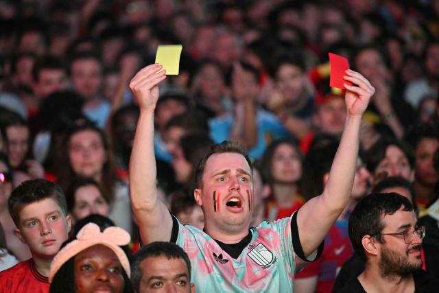 A fan holds a yellow and a red card at a fan zone as he watches the 2026 World Cup quarter final football match between Spain and Belgium in Uccle near Brussels on July 10, 2026. (Photo by NICOLAS TUCAT / AFP)
