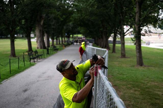 Workers install privacy mesh on fencing along the Lincoln Memorial Reflecting pool on the National Mall in Washington, DC on July 10, 2026. (Photo by Kent Nishimura / AFP)