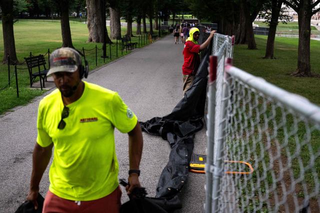 Workers install privacy mesh on fencing along the Lincoln Memorial Reflecting pool on the National Mall in Washington, DC on July 10, 2026. (Photo by Kent Nishimura / AFP)
