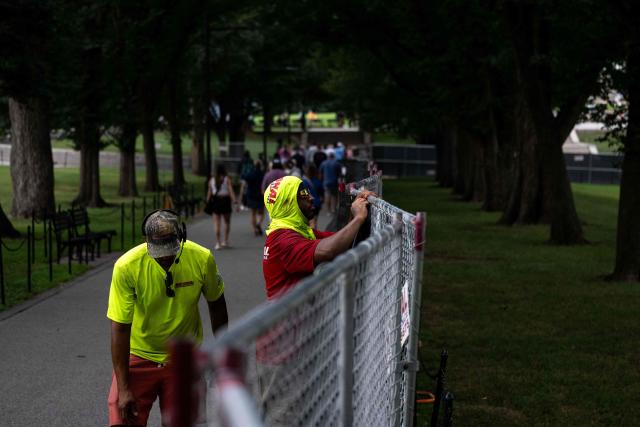 Workers install privacy mesh on fencing along the Lincoln Memorial Reflecting pool on the National Mall in Washington, DC on July 10, 2026. (Photo by Kent Nishimura / AFP)