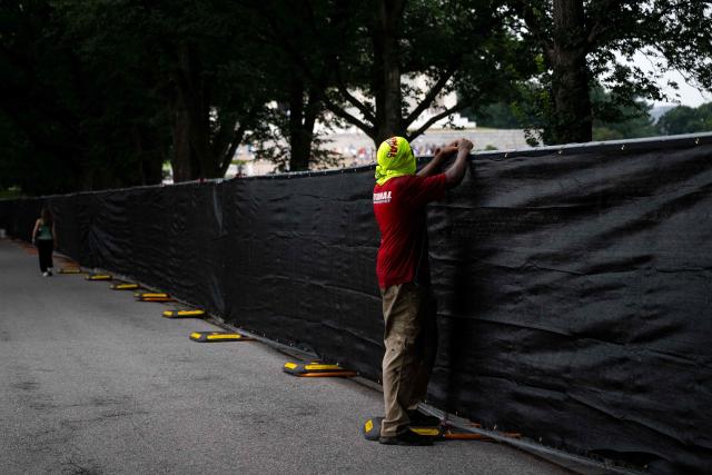 Workers install privacy mesh on fencing along the Lincoln Memorial Reflecting pool on the National Mall in Washington, DC on July 10, 2026. (Photo by Kent Nishimura / AFP)