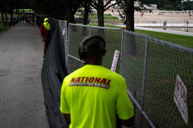 Workers install privacy mesh on fencing along the Lincoln Memorial Reflecting pool on the National Mall in Washington, DC on July 10, 2026. (Photo by Kent Nishimura / AFP)