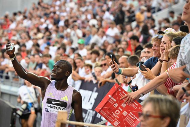 Kenya's Emmanuel Wanyonyi (L) takes a selfie with fans after setting a new World Record in the men's 1000m during the Diamond League athletics meeting at the Stade Louis II in Monaco on July 10, 2026. (Photo by Frederic Dides / AFP)